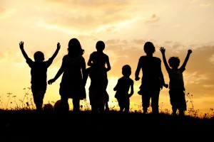 Silhouette, group of happy children playing on meadow, sunset, summertime